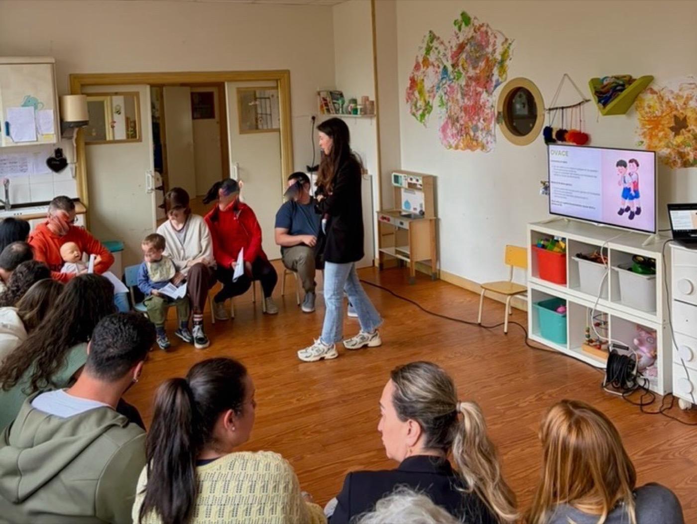Taller de primeros auxilios con las familias sentadas en círculo en el aula